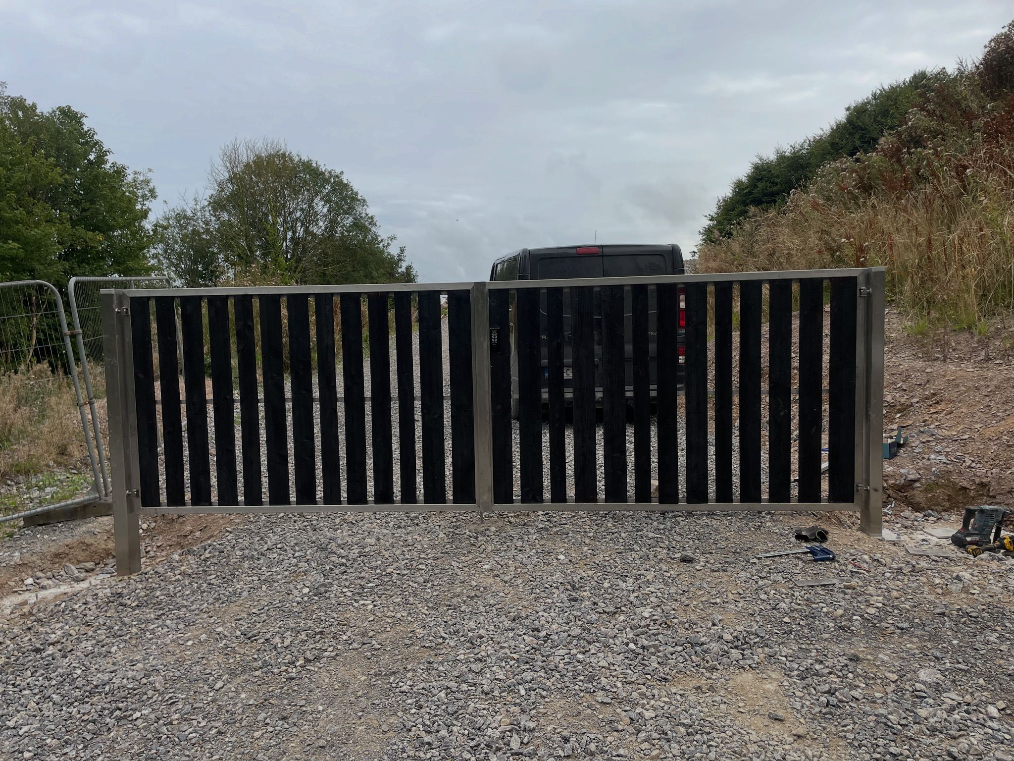 Double steel gate with stainless steel posts and vertical black slats
