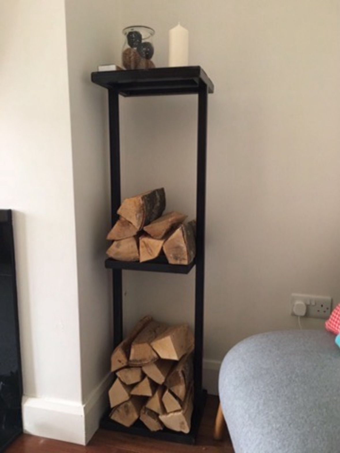 Slim black powder-coated steel log rack with display shelf