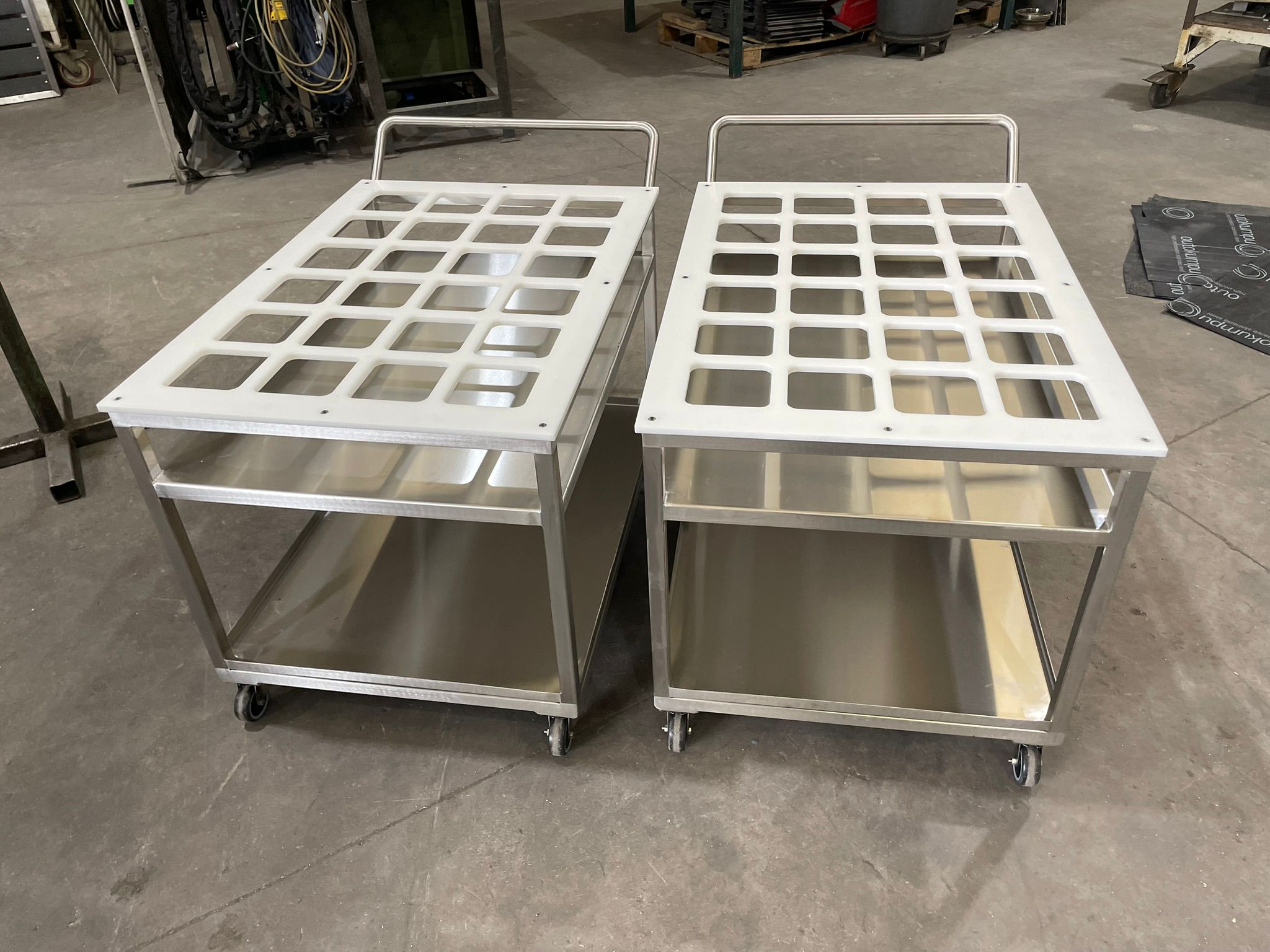 Pair of stainless steel pharmaceutical trolleys with perforated tops and lower shelf